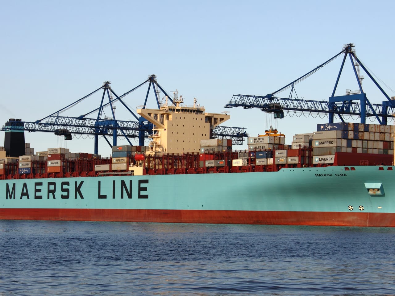 Wielki kontenerowiec morski Maersk z tysiącami kolorowych kontenerów płynący po spokojnej wodzie
