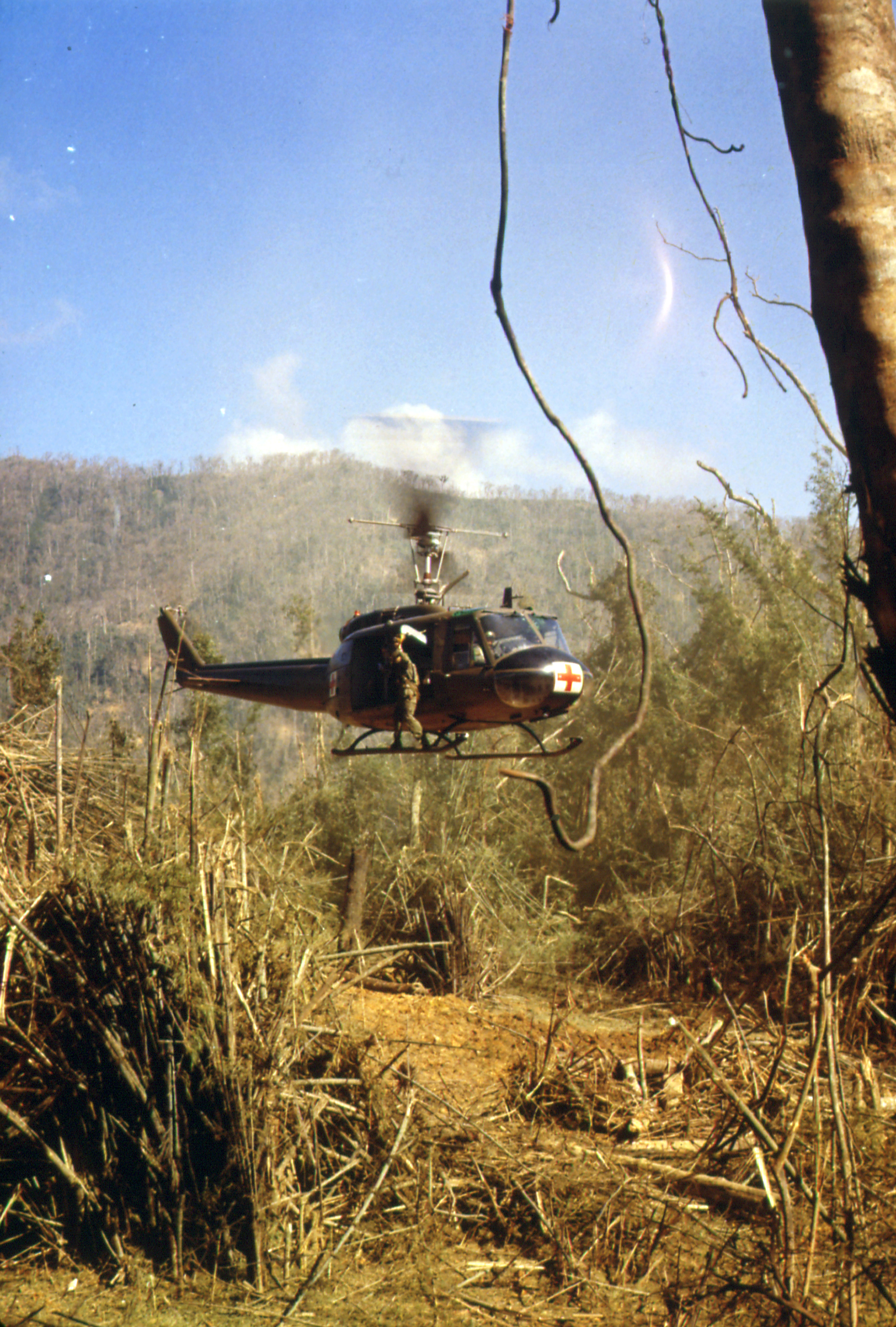 Śmigłowiec UH-1D Dustoff podrywa się pionowo ze strefy lądowania w gęstej dżungli po podjęciu rannego