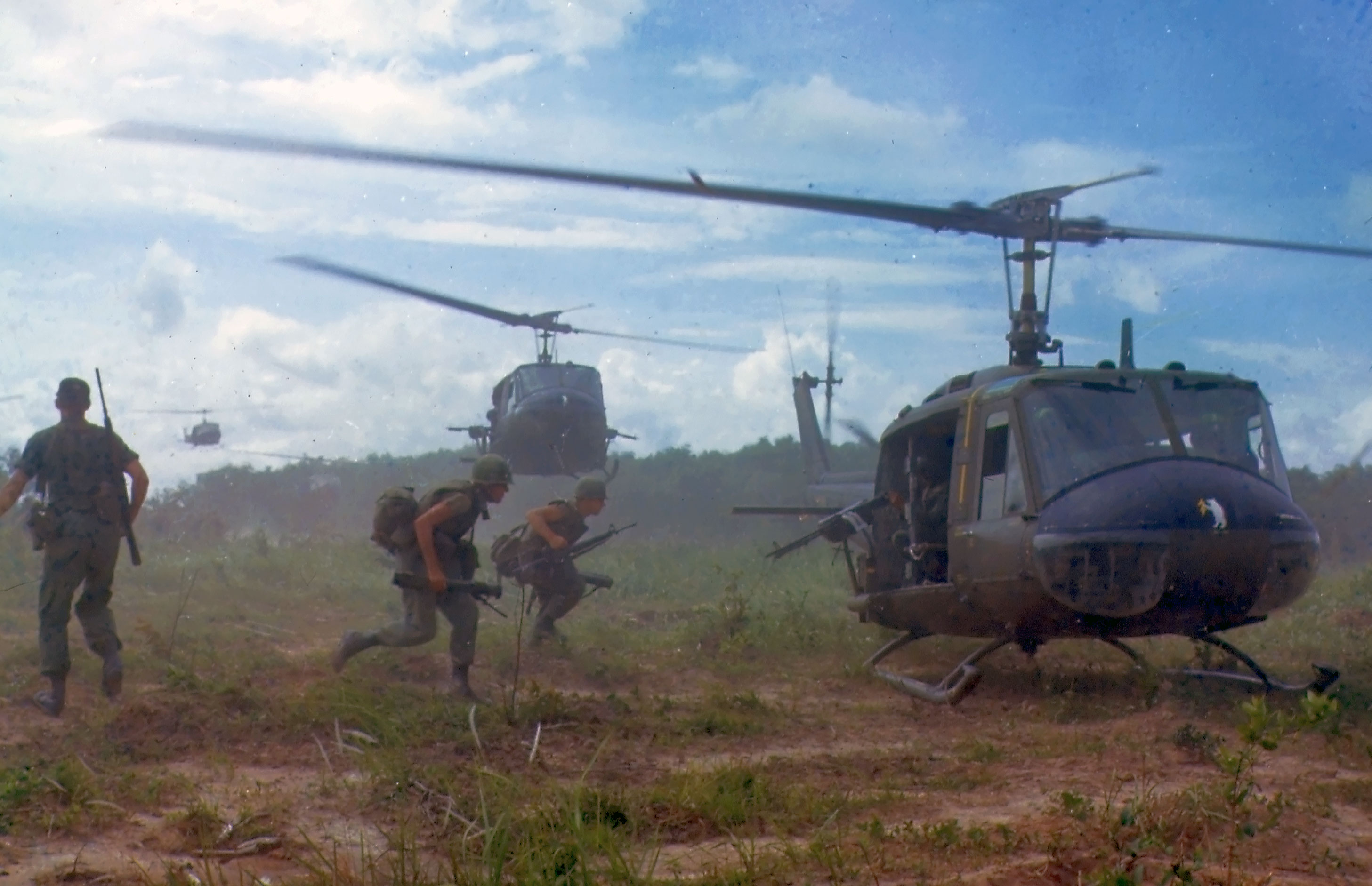 Śmigłowce Bell UH-1D Iroquois desantują żołnierzy piechoty w wysokiej trawie słoniowej podczas operacji Wahiawa w Wietnamie Południowym w 1966 roku