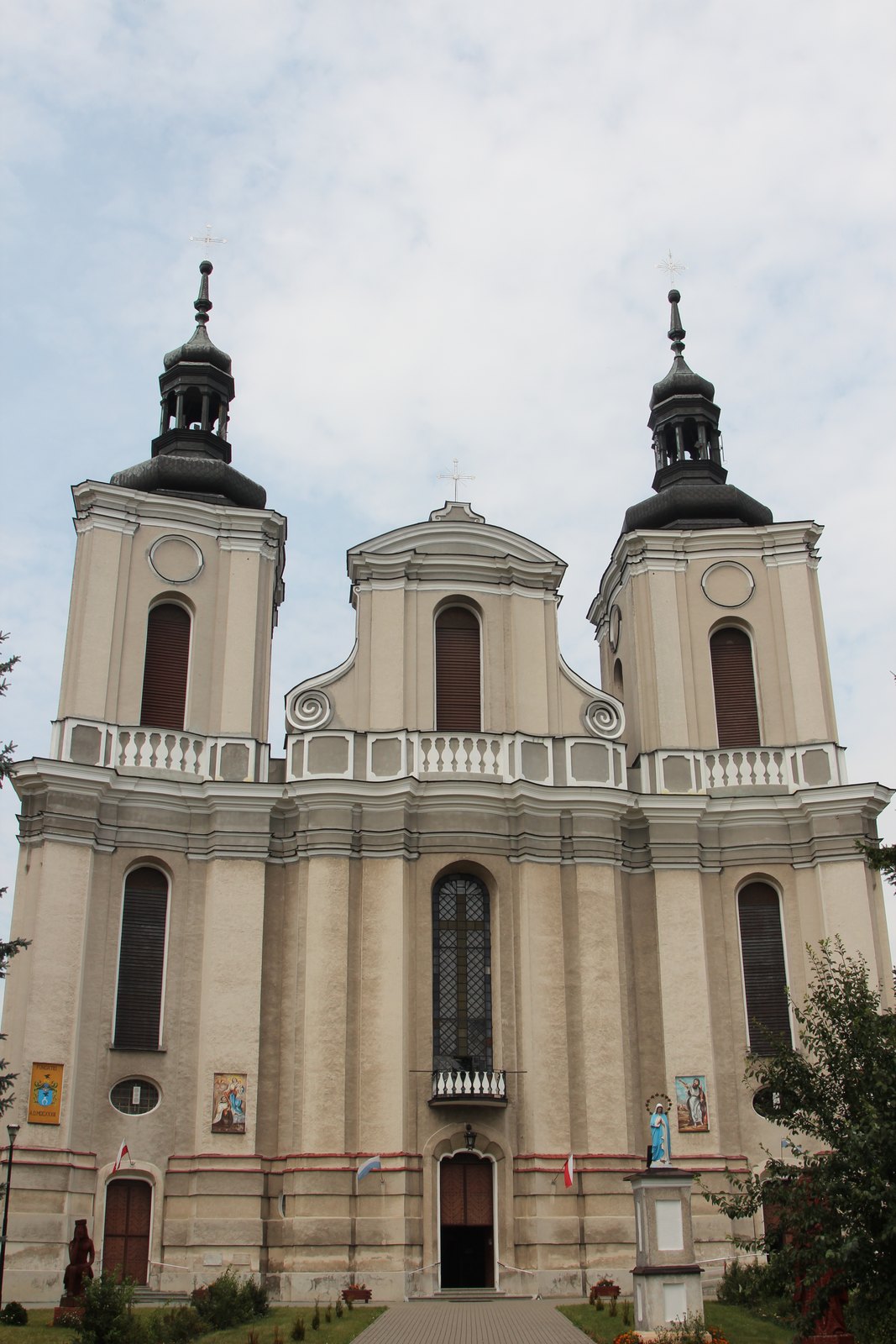 Barokowa fasada kościoła Nawiedzenia Najświętszej Marii Panny w Woli Gułowskiej z dwiema wieżami zwieńczonymi hełmami