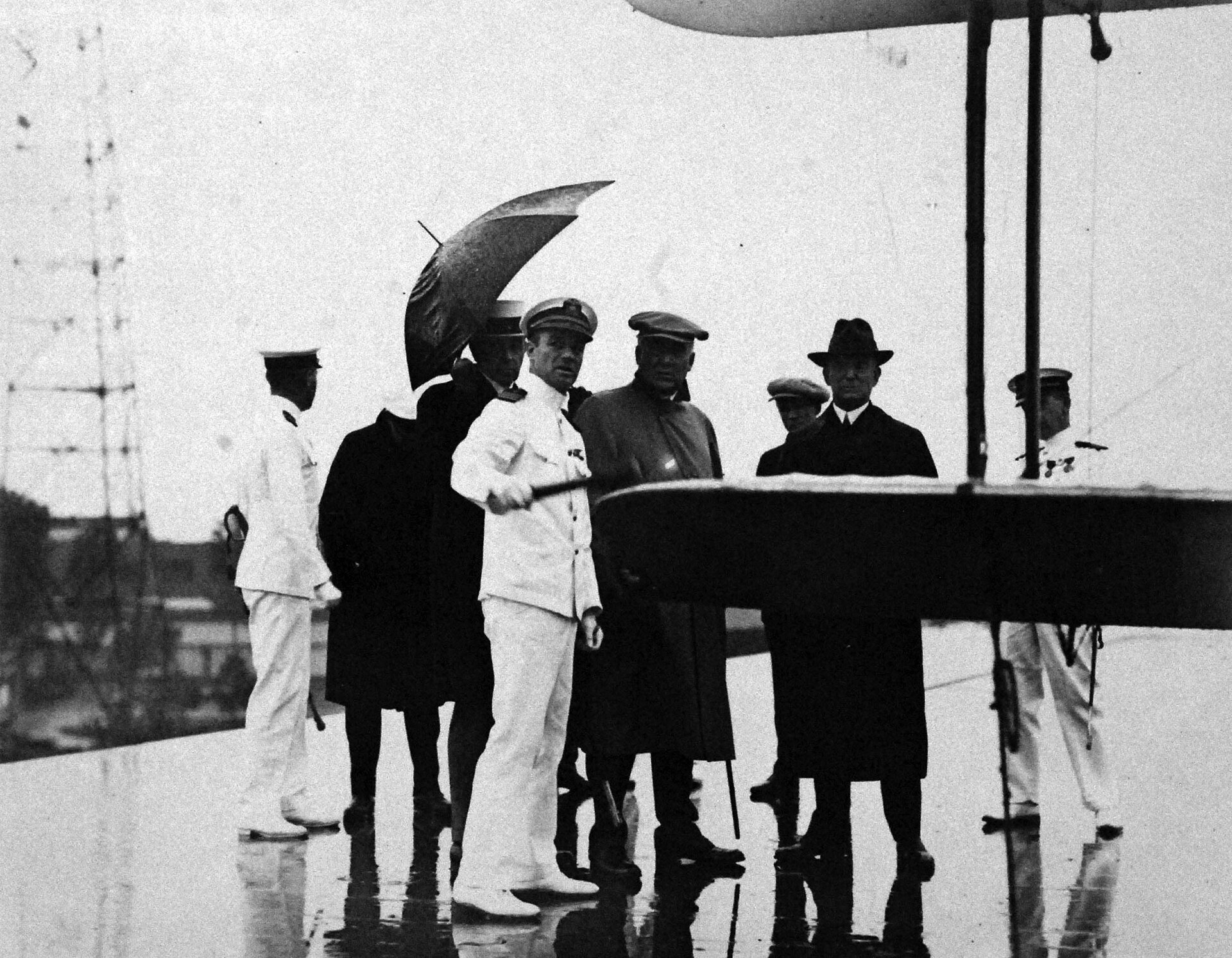 Prezydent Warren Harding w kapeluszu i płaszczu stoi z oficerami marynarki na pokładzie lotniskowca