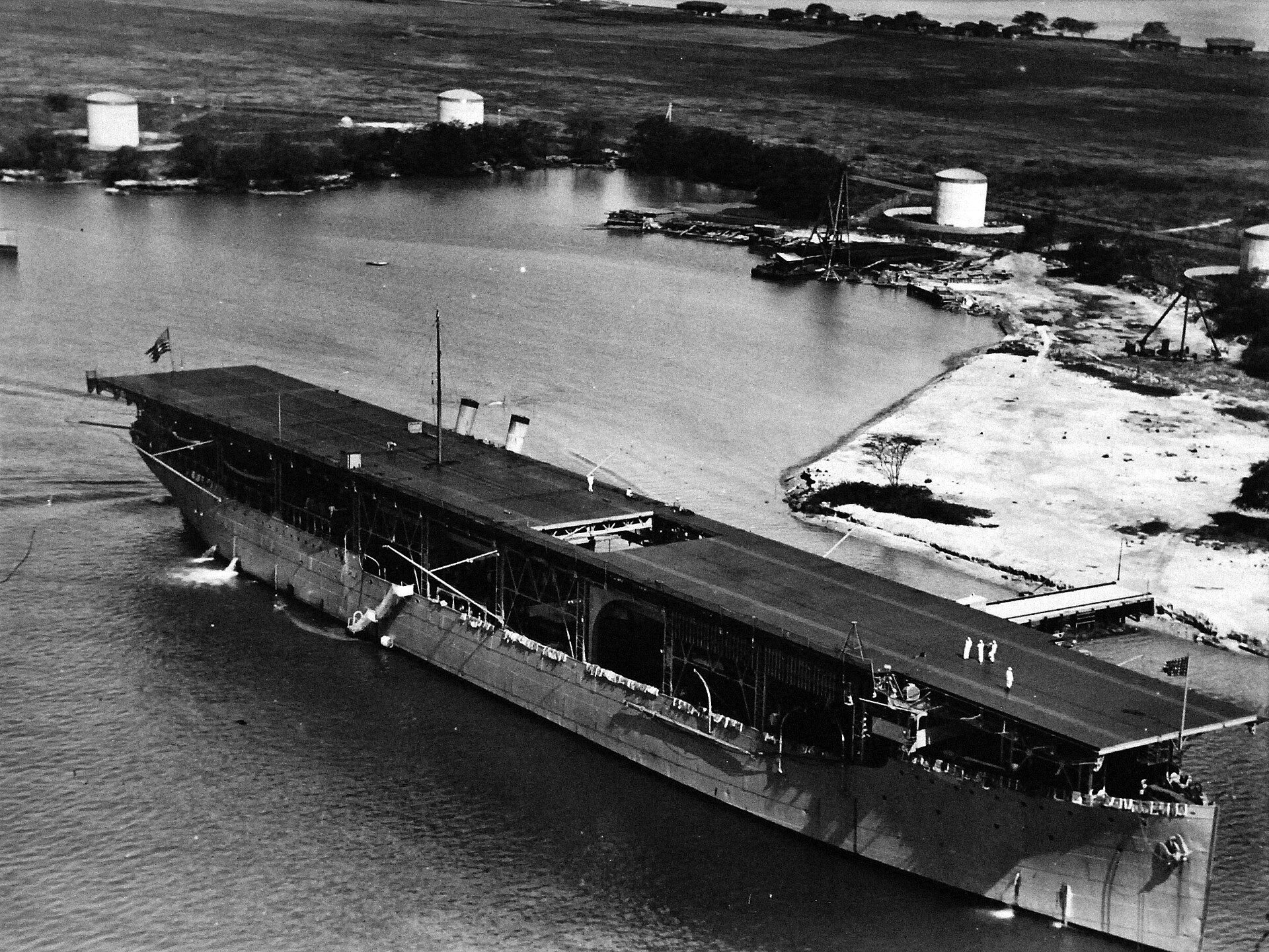 Lotniskowiec Langley przepływa obok zbiorników paliwa w porcie Pearl Harbor