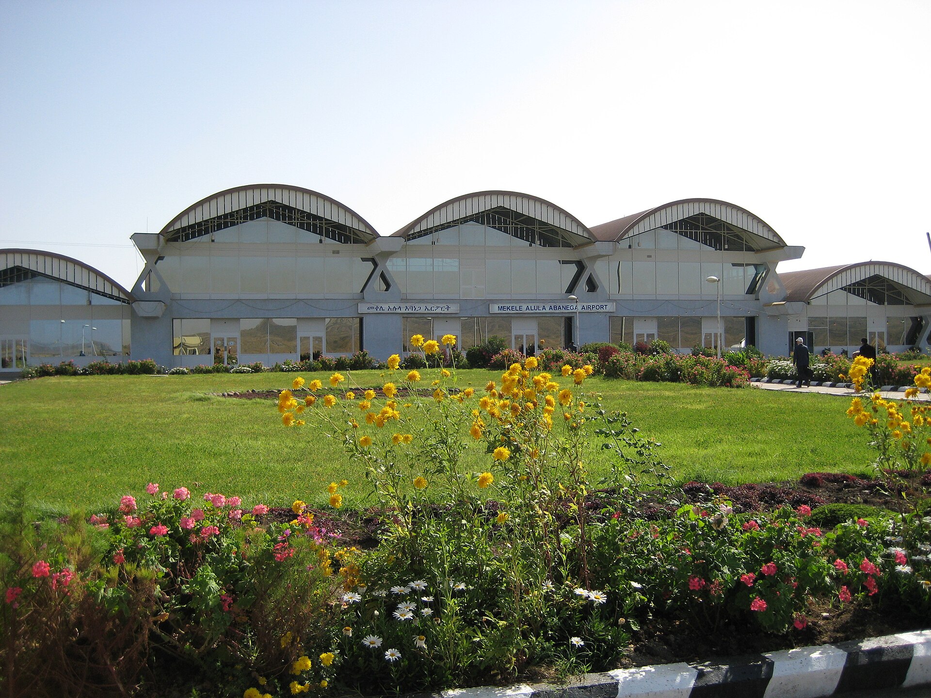 Terminal portu lotniczego w Mekelle z łukowatym dachem, przed nim trawnik i kwiaty