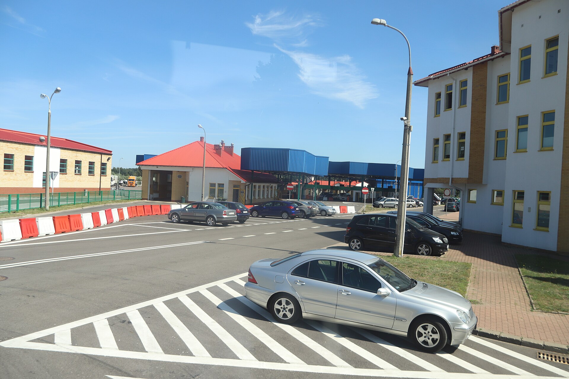 Parking i budynki przejścia granicznego, niebieskie zadaszenie odprawy, samochody przy barierkach