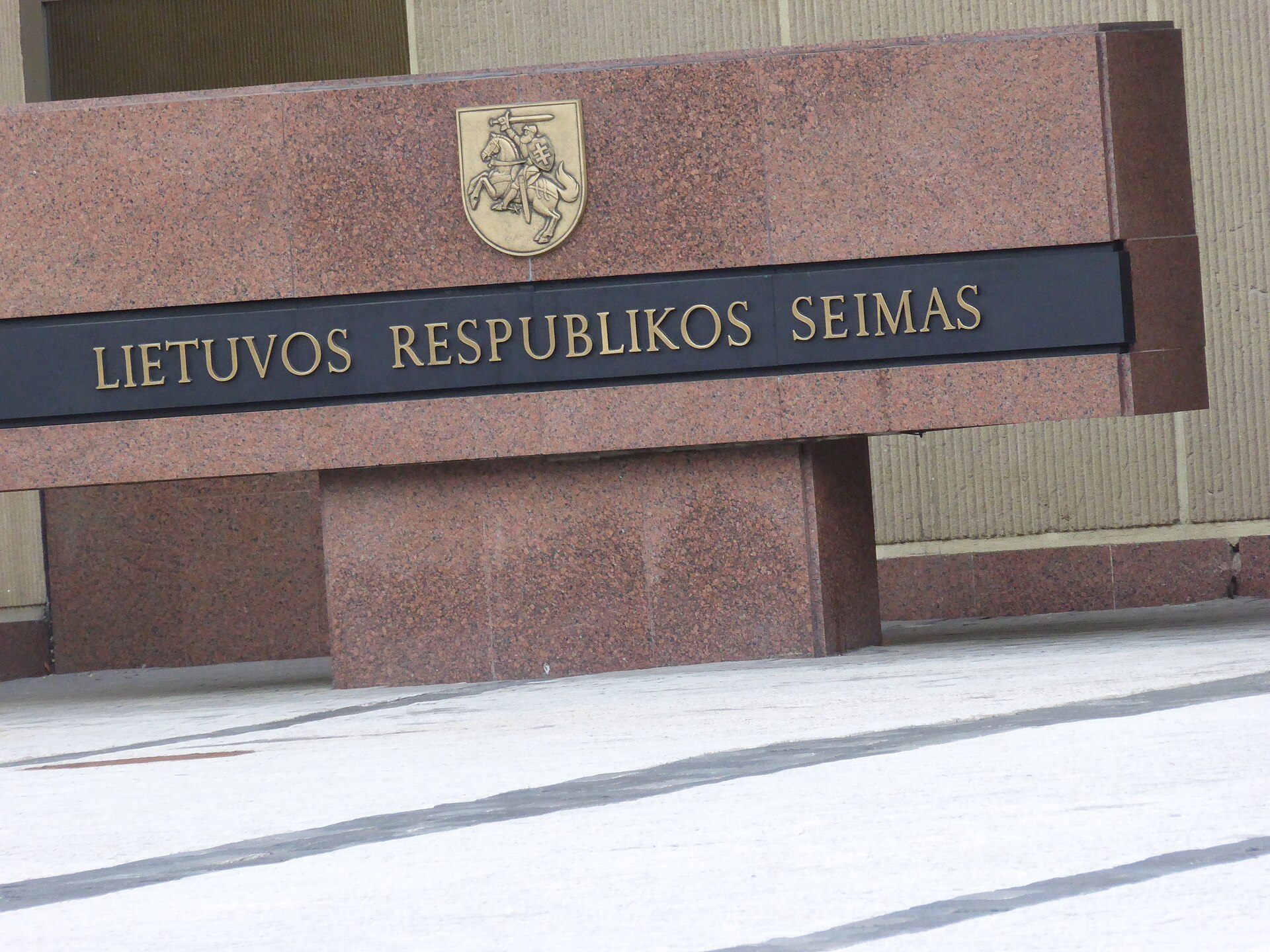 Granitowy monument z herbem Pogoni i napisem Lietuvos Respublikos Seimas przed budynkiem