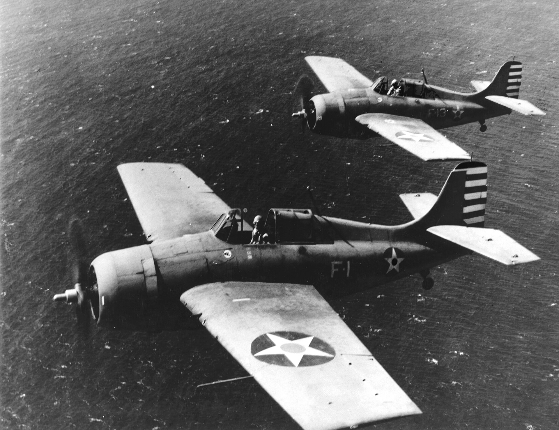 Dwa myśliwce Grumman F4F Wildcat w locie nad oceanem, na bliższym oznaczenie F-1