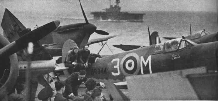 Myśliwce Spitfire z oznaczeniami RAF na pokładzie lotniskowca, w tle drugi lotniskowiec